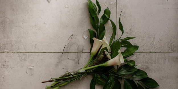 Ramo de flores sobre suelo de cerámica con un jarrón de cristal roto
