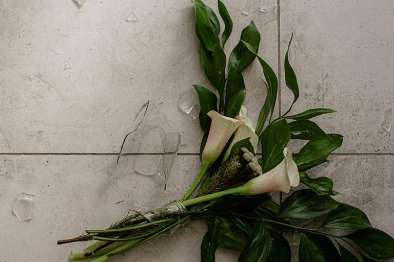 terapia-emocional-coach-oscar-ayuda Ramo de flores sobre suelo de cerámica con un jarrón de cristal roto